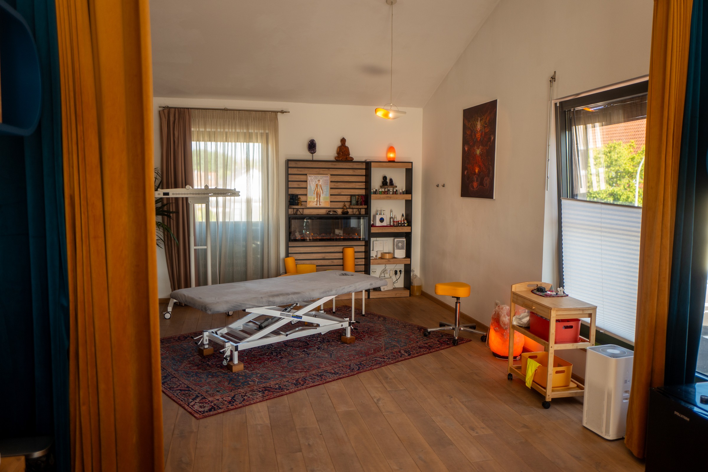 Behandlungsraum mit höhenverstellbarer Liege, Regal mit Ölen und Salzlampen